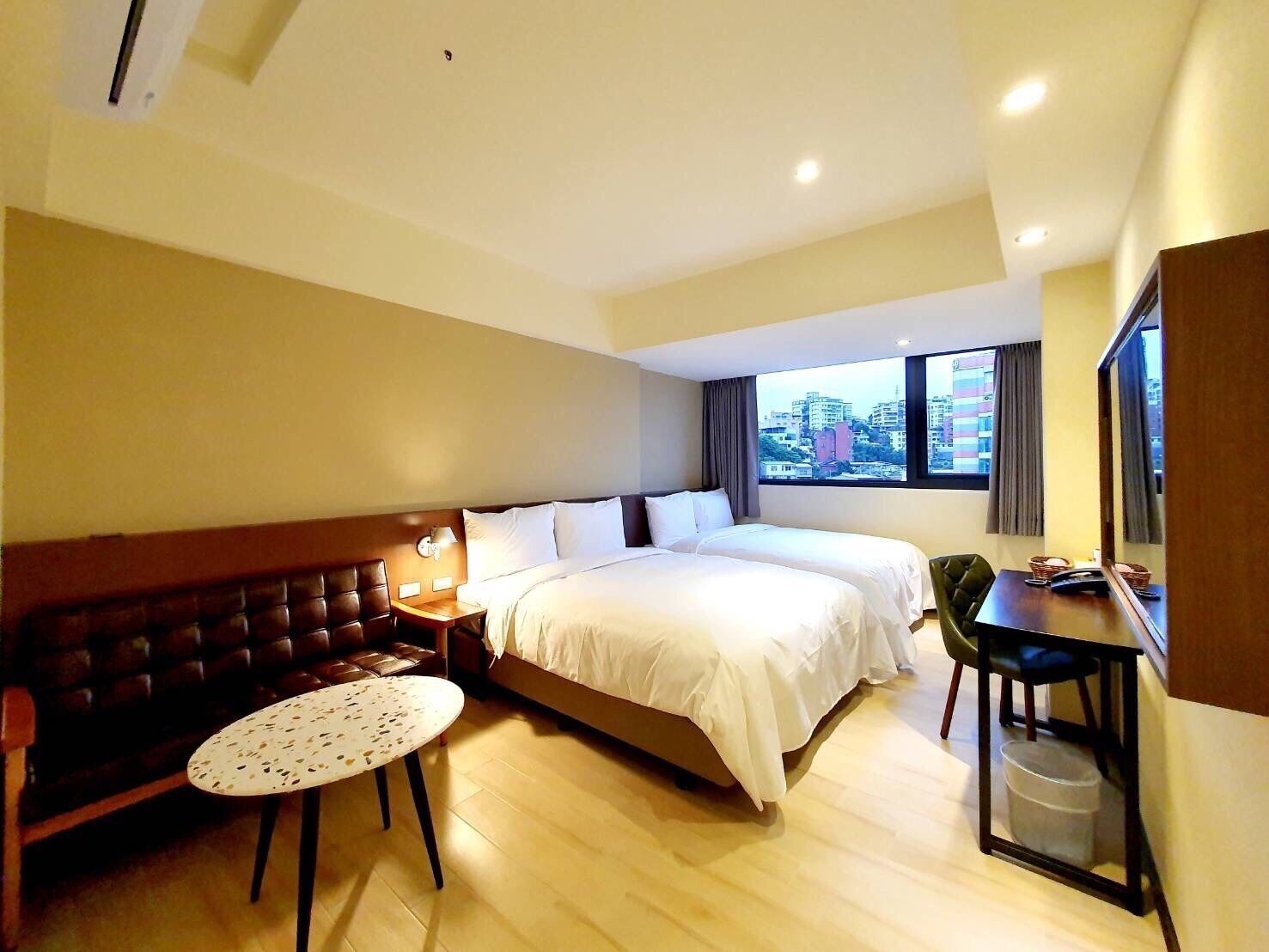 A hotel room with a large bed, a sofa, a small table, and a desk with a chair.