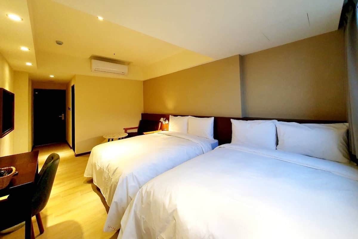 Habitación de hotel con dos camas, un escritorio y una silla.
