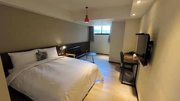 Una habitación de hotel moderna con una cama grande, un escritorio, una silla y un televisor montado en la pared.