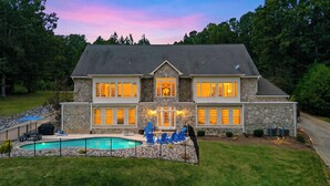 A two-story house with a stone facade, a swimming pool, and a well-maintained lawn. - Sleeps 20! Lakefront + Private Dock + Pool | Whitetail Cove By AvantStay (Troutman)