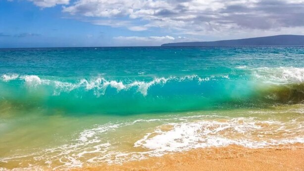 Ein Strand mit klarem türkisblauem Wasser und einem sandigen Ufer.