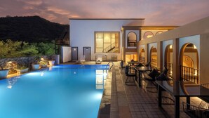 A modern outdoor pool area with a clear view of a building, a staircase, and outdoor seating. - The Montail Udaipur (Udaipur)