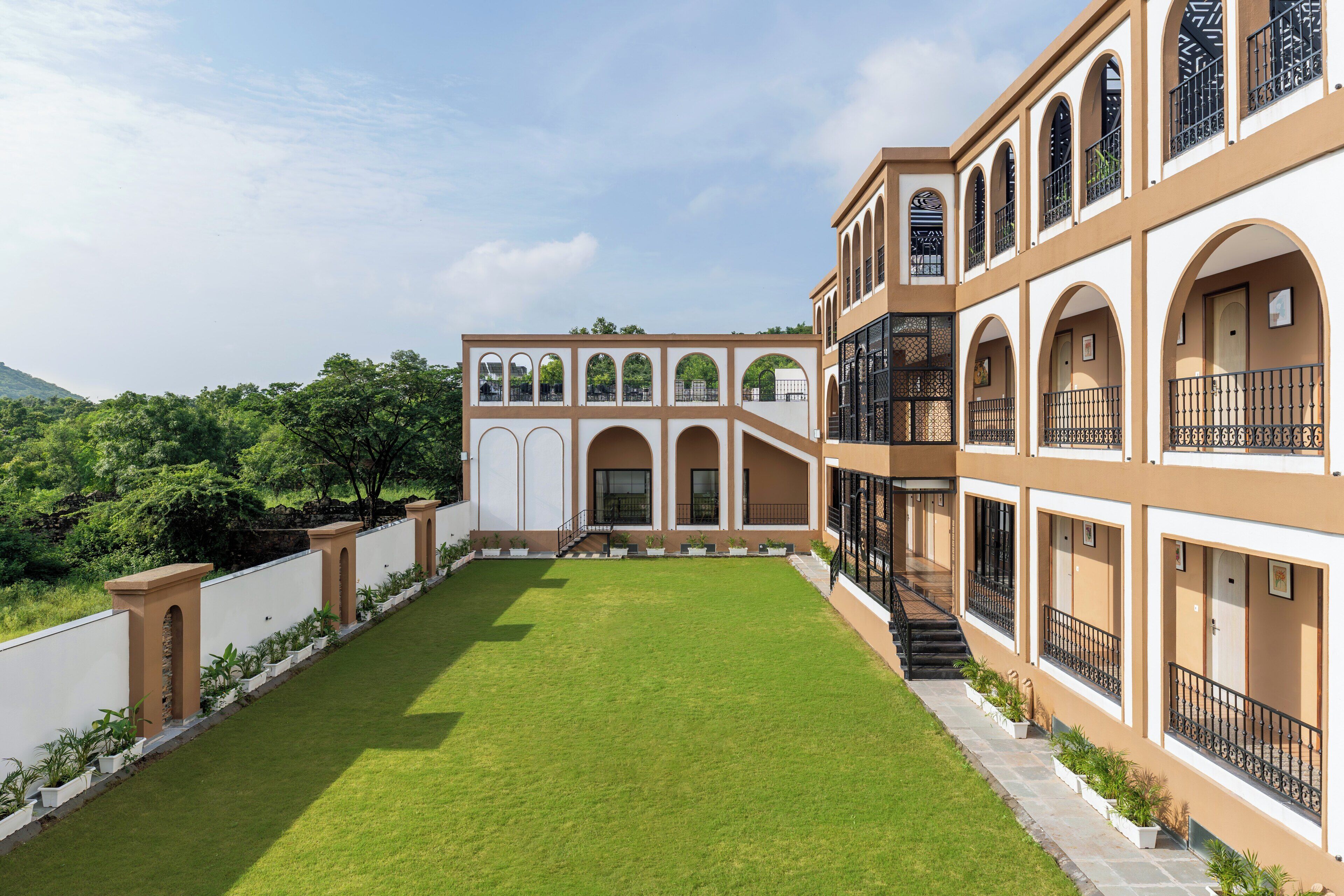 A courtyard with a central lawn, surrounded by buildings with arched windows and balconies.