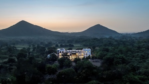 A hotel with a modern design, surrounded by lush greenery and hills in the background. - The Montail Udaipur (Udaipur)