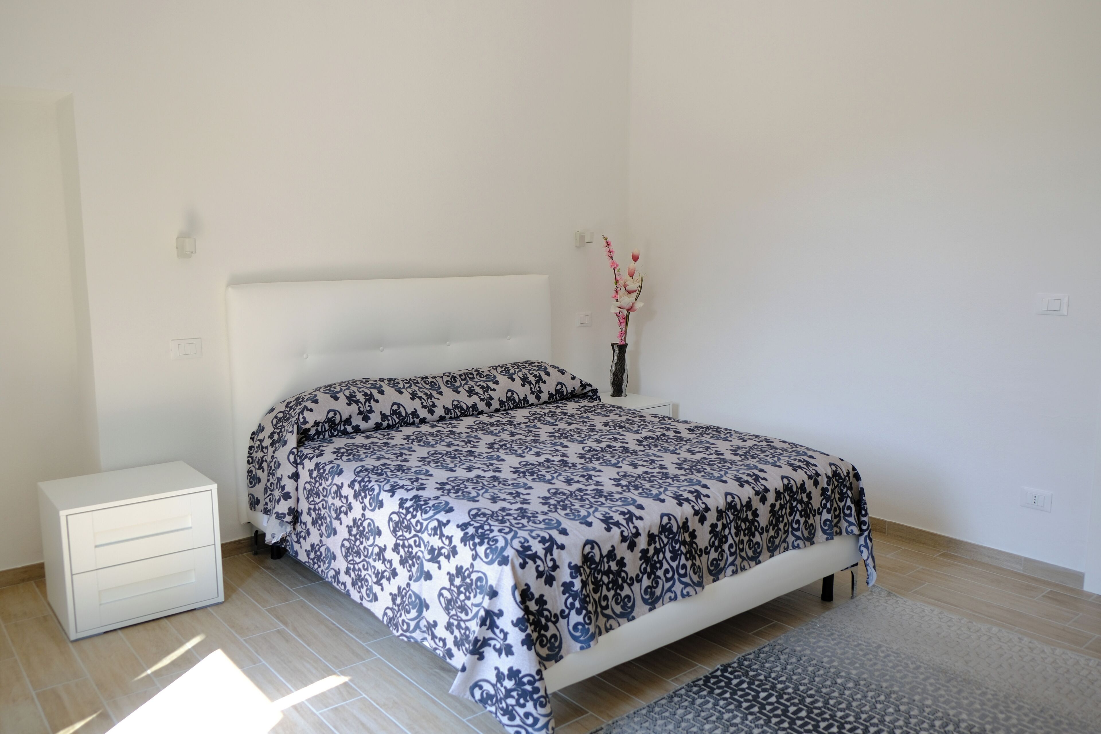 A bedroom with a bed, a bedside table, and a nightstand.