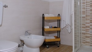 A bathroom with a toilet, bidet, and a glass-enclosed shower area. - Albergo Tenco by Bottega (Ricaldone)