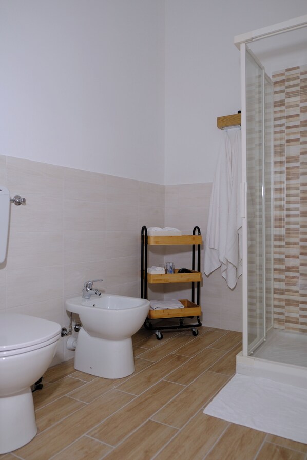Un baño con inodoro, bidé y ducha con mampara de vidrio.