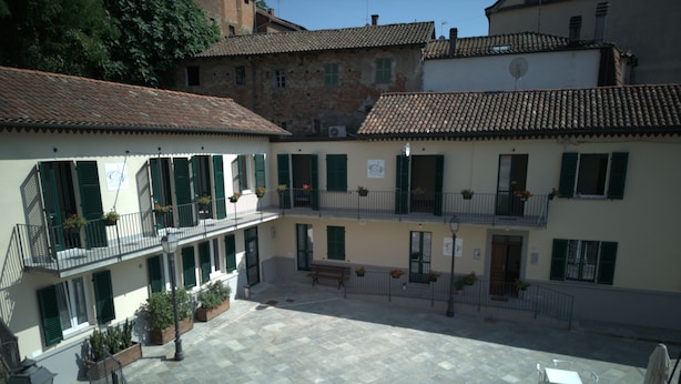 A courtyard with outdoor seating, a staircase, and buildings with balconies. - Albergo Tenco by Bottega (Ricaldone)