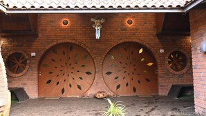 A building entrance with two large wooden doors featuring leaf patterns, a tiled roof, and a small plant in the foreground. - Bamboo and Bricks Resorts (Paud)