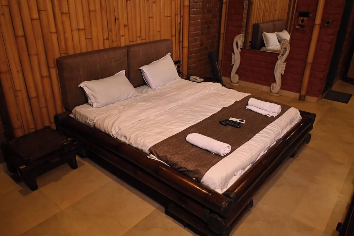 A neatly made bed with pillows and a blanket, a bedside table with a phone, and a wooden headboard.