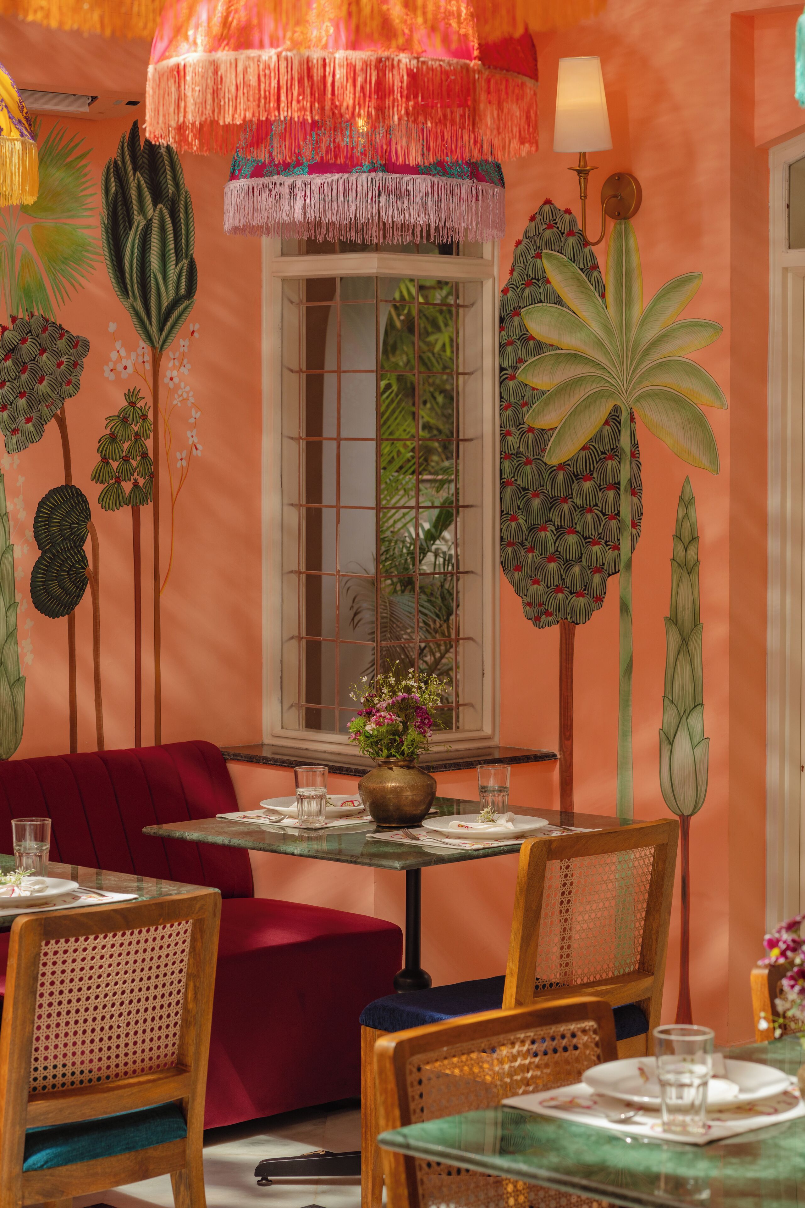 Un comedor con una mesa preparada para dos, un sofá rojo y una ventana con vistas a zonas verdes.