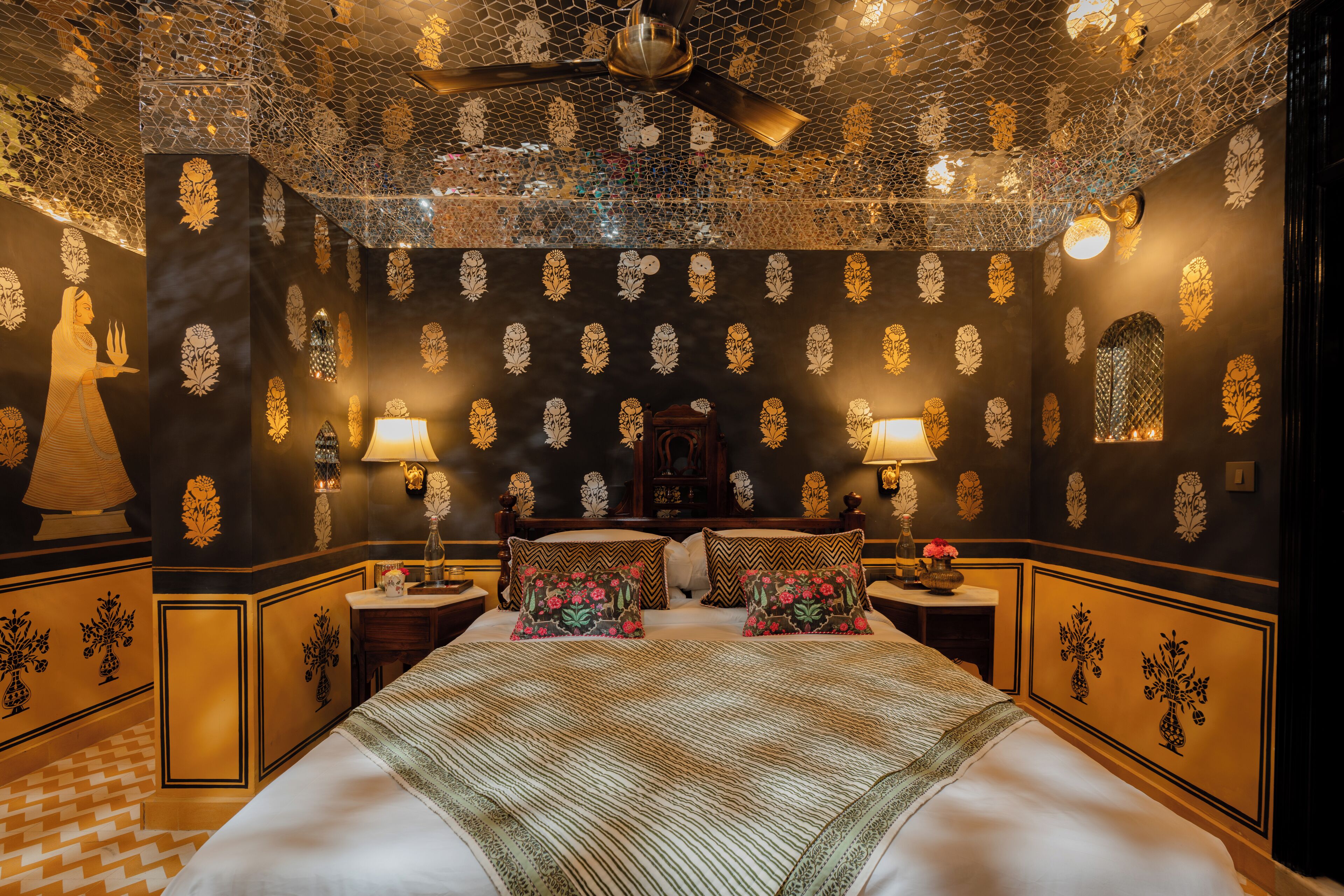 A luxurious bedroom with a large bed, decorative wall panels, and a ceiling fan.