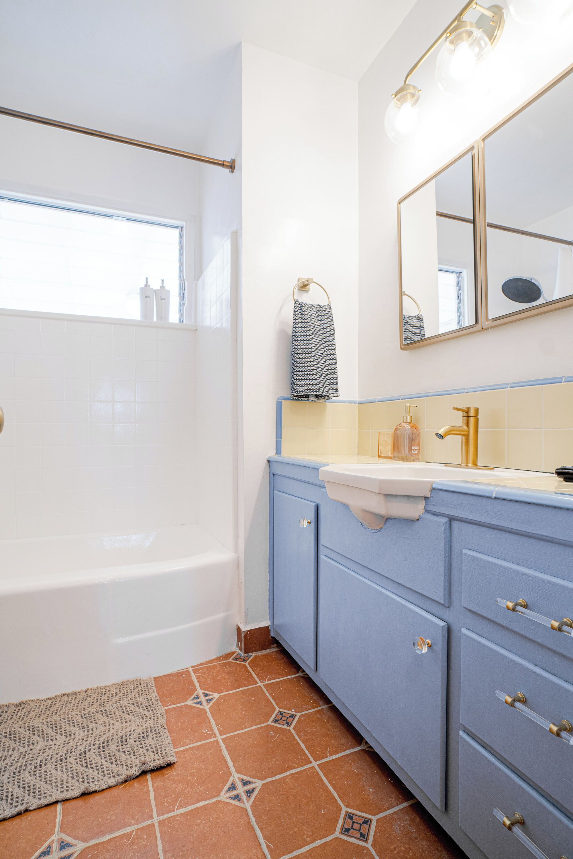 A bathroom with a bathtub, a sink with a gold faucet, and a mirror above the sink.