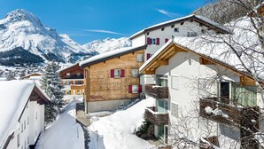 A snow-covered mountain with a chalet-style building in the foreground.