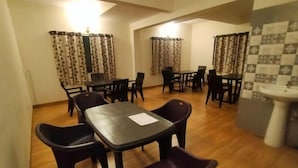 Een eethoek met een tafel, stoelen, een spoelbak en decoratieve gordijnen.