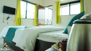 Een hotelkamer met twee bedden, een aan de muur bevestigde televisie en een raam met gele gordijnen.