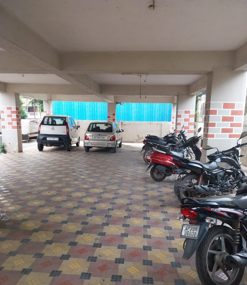 Un área de estacionamiento techada con piso estampado, dos autos y varias motocicletas.
