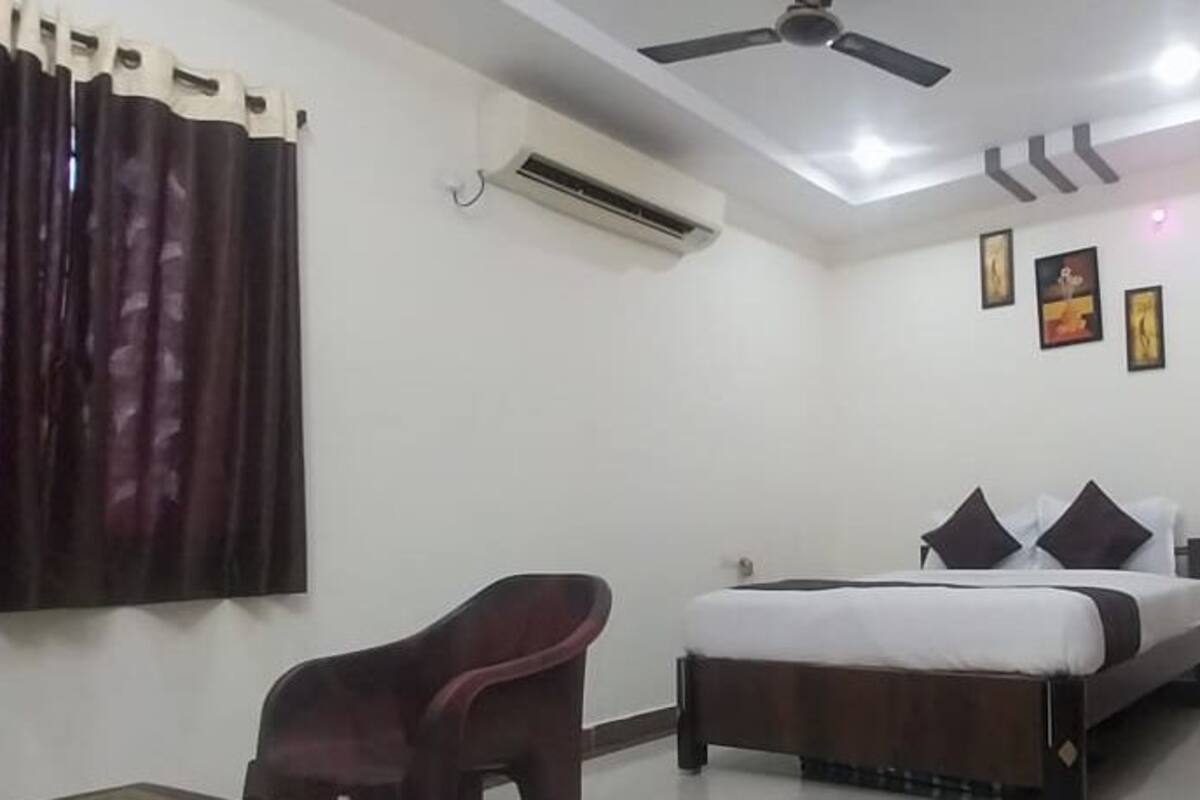 A bedroom with a bed, a chair, a ceiling fan, and wall-mounted air conditioning.