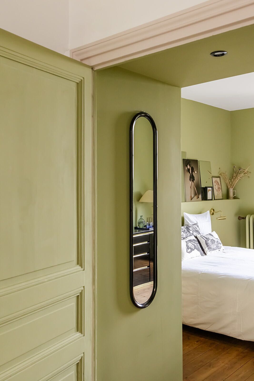 Una habitación con una cama, una mesita de noche, un espejo y una pared decorada con cuadros.
