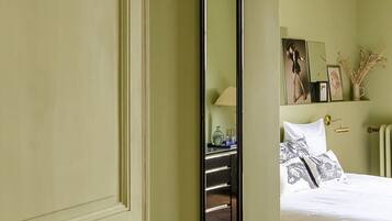 Una habitación con una cama, una mesita de noche, un espejo y una pared decorada con cuadros.