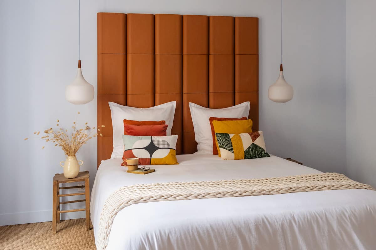 A neatly made bed with a white comforter and a beige knitted throw.