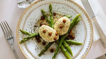 A plate of food with asparagus and a white plate with a gold rim.