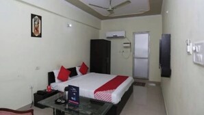 A hotel room with a bed, a glass coffee table, a wardrobe, an air conditioning unit, and a door. - Hotel S K Palace (Lucknow)