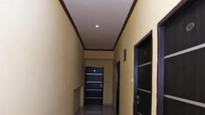 A narrow hallway with a tiled floor, beige walls, and a dark door on the right. - Hotel S K Palace (Lucknow)