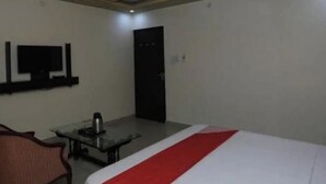 A hotel room with a bed, a television, a desk with a coffee maker, and a ceiling fan. - Hotel S K Palace (Lucknow)