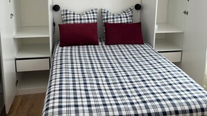 A bedroom with a bed, two red pillows, a hanging light, and white built-in wardrobes. - Cosy apartment 1 min from Paris (Charenton-le-Pont)