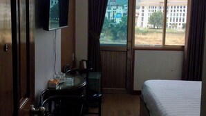 A hotel room with a bed, a desk with a chair, a television mounted on the wall, and a window with curtains. - A10 Thuy Hoa Hotel LC  - by BAY LUXURY (Lao Cai)