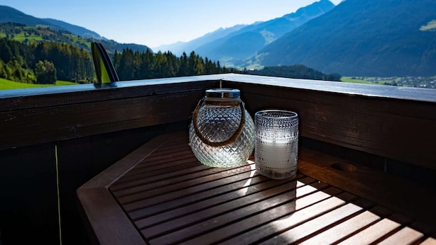 A wooden deck with two glass containers and a metal candle holder. - Farmhouse in Hollersbach with Mountain Views (Hollersbach im Pinzgau)