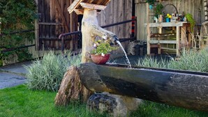 A rustic outdoor water feature with a wooden structure, a potted plant, and a wooden table with various items. - Farmhouse in Hollersbach with Mountain Views (Hollersbach im Pinzgau)