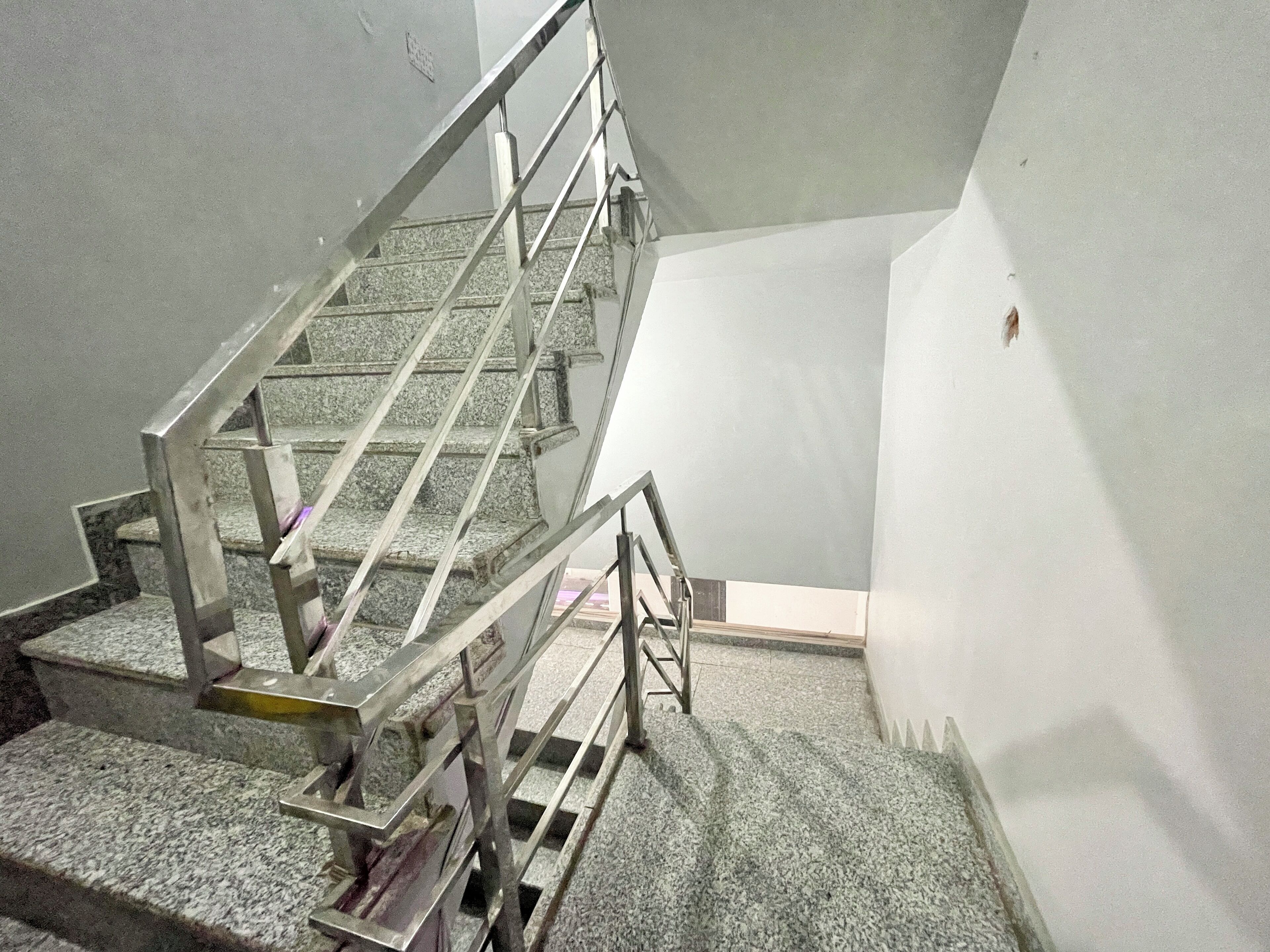 A staircase with metal railings and granite steps, leading to a higher floor.
