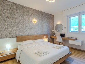 Ein modernes Schlafzimmer mit Bett, Nachttischen, einem Schreibtisch und einem Fenster.