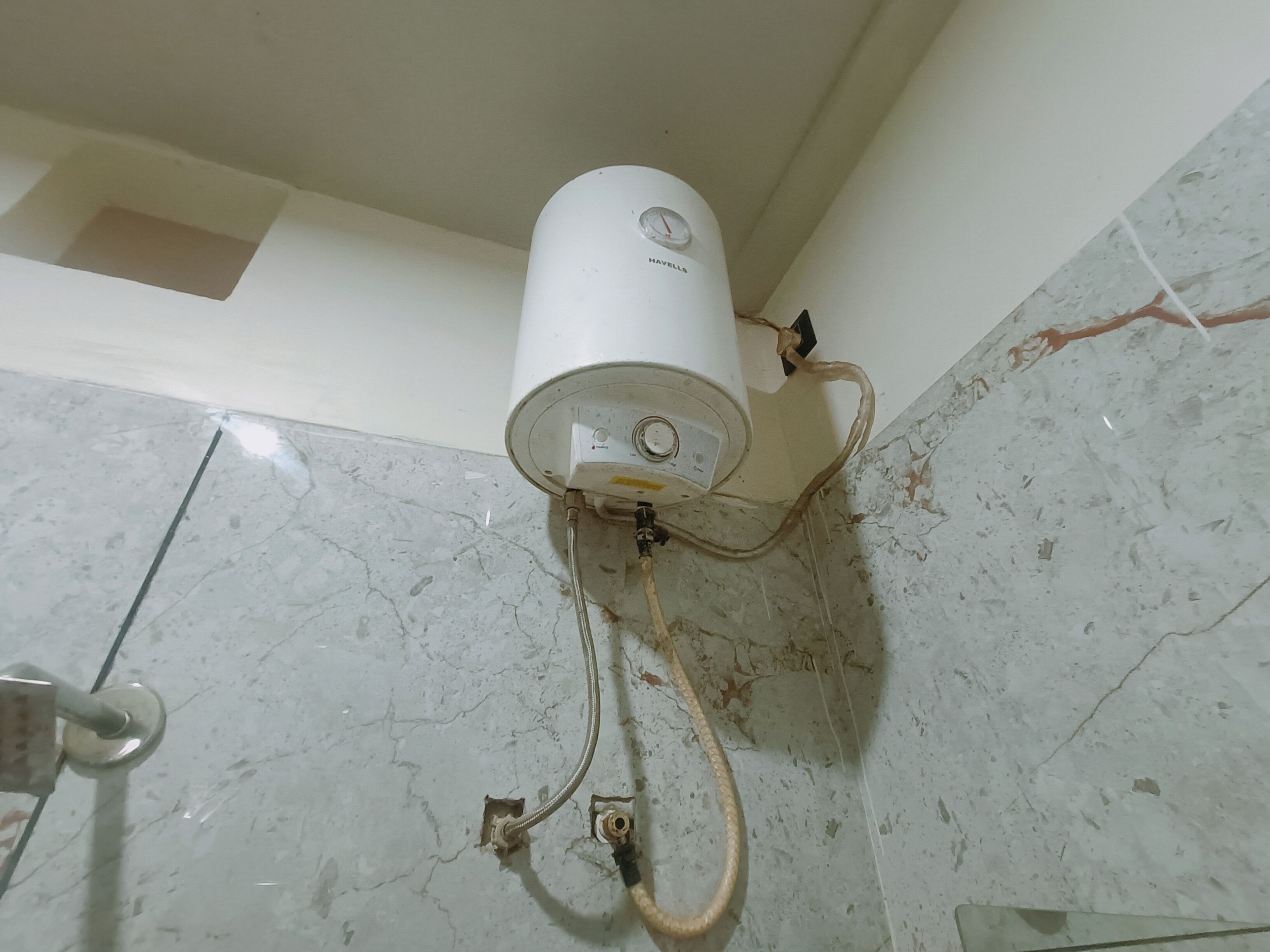 A white water heater mounted on a wall with visible pipes and a control panel.