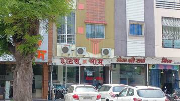 A building with multiple shops on the ground floor, including a hotel and a restaurant. There are several parked cars in front.