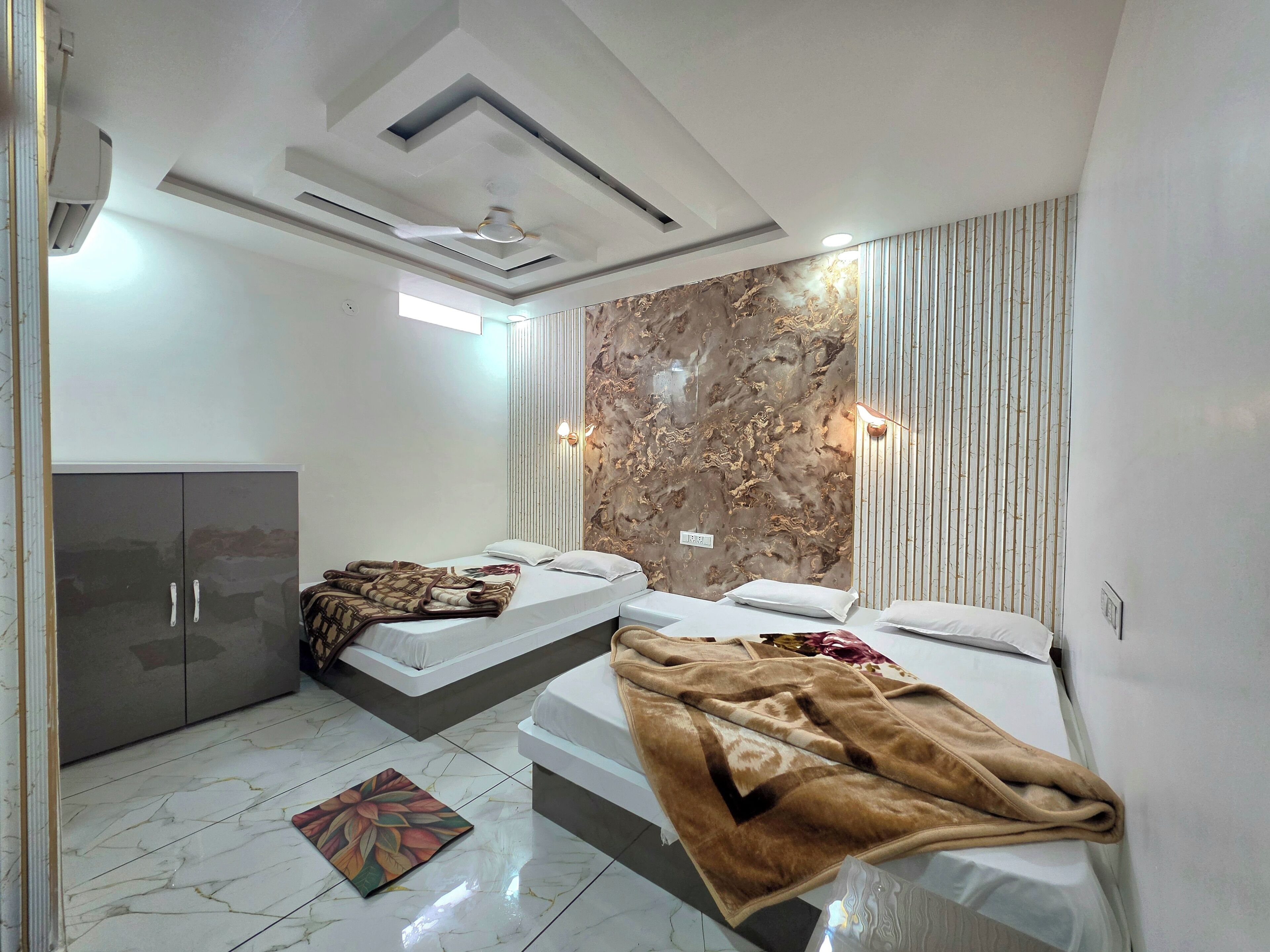 A modern bedroom with two beds, a wardrobe, and a decorative wall.