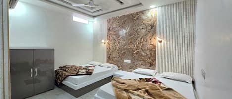 A modern bedroom with two beds, a wardrobe, and a decorative wall.