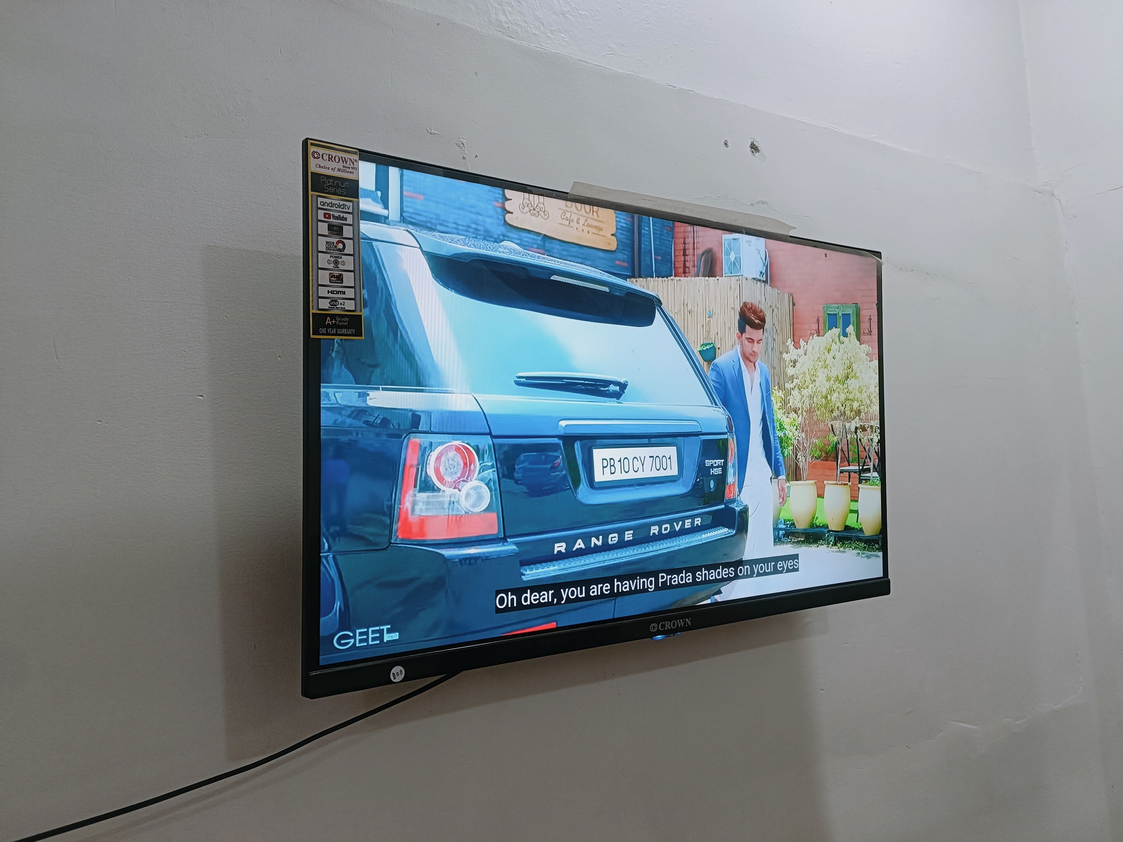 A television mounted on a wall displaying a Range Rover with a license plate.