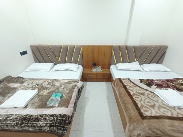 Two single beds with striped headboards, white linens, and a nightstand with a water bottle and toiletries.