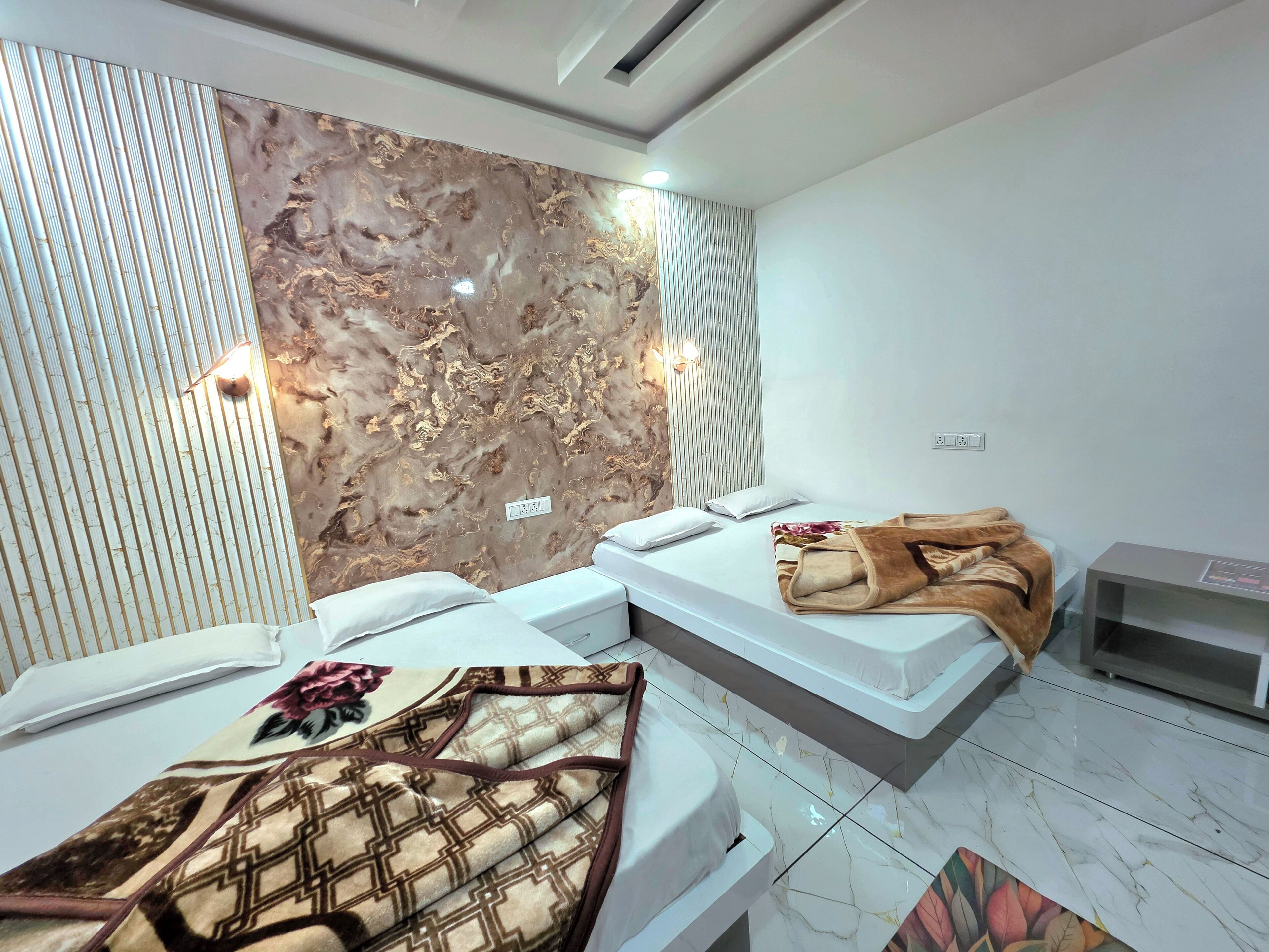 Una habitación de hotel moderna con dos camas, una pared con diseño de mármol y una mesita de noche pequeña.
