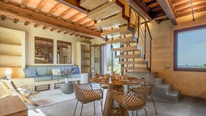 A modern interior with a wooden ceiling, a spiral staircase, a round dining table with chairs, and a large window. - Punteriolo Family Apartment, Nice Garden Pool Montaione (Montaione)