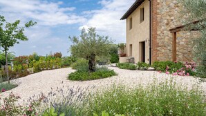 A stone building with a gravel driveway and a garden with various plants and flowers. - Punteriolo Family Apartment, Nice Garden Pool Montaione (Montaione)