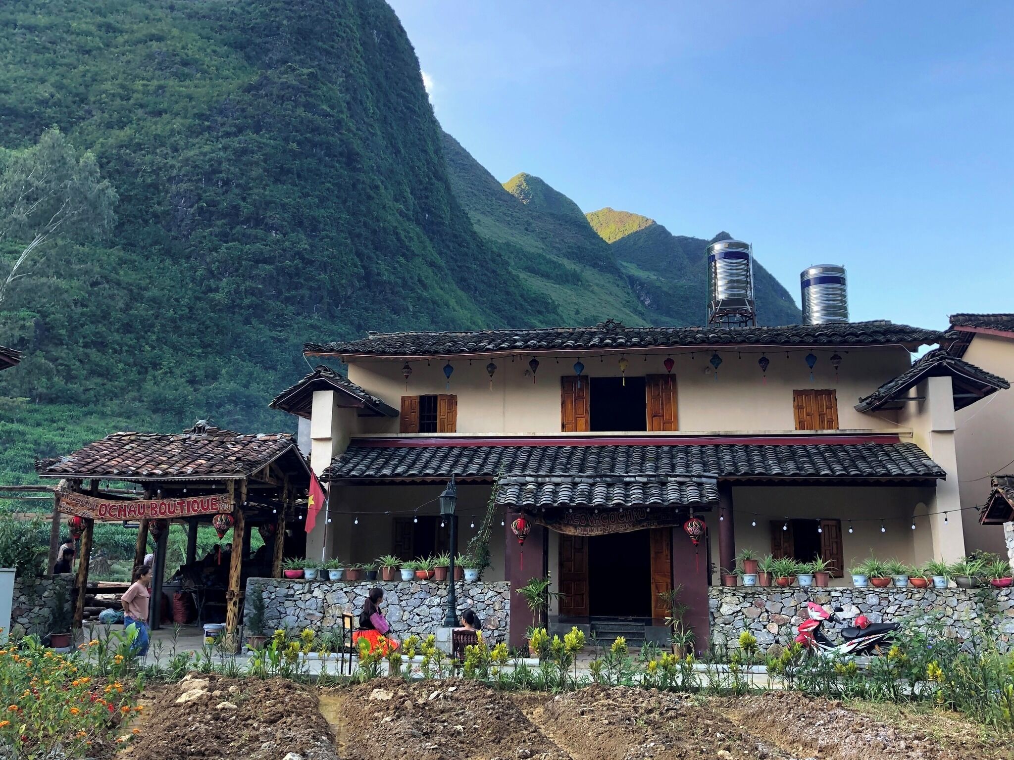 Un bâtiment traditionnel avec un toit en tuiles, un mur en pierre et des plantes en pot.