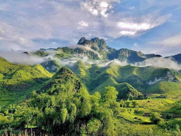 Un paisaje montañoso con colinas verdes y un pico destacado.