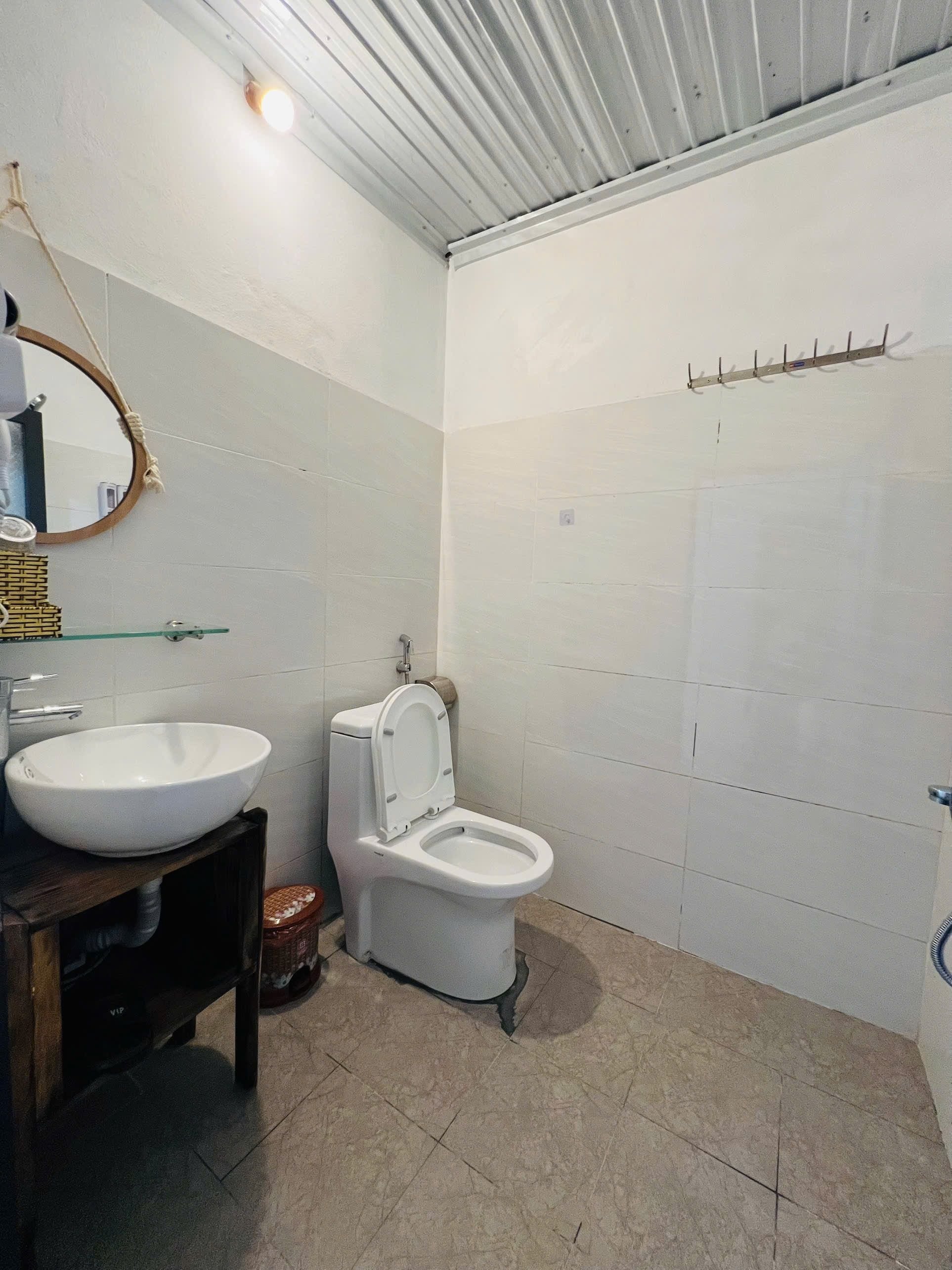 Une salle de bain avec un lavabo, des toilettes et un miroir, le tout de couleur blanche.