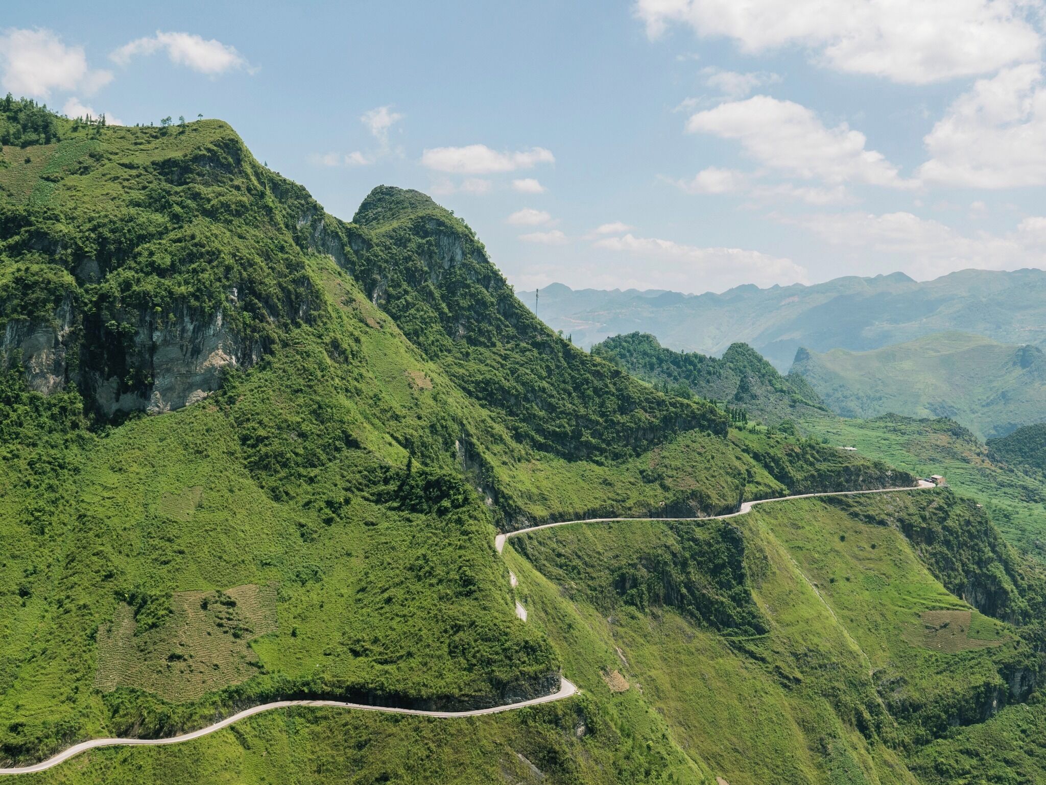 A winding road through lush green hills with a clear sky.