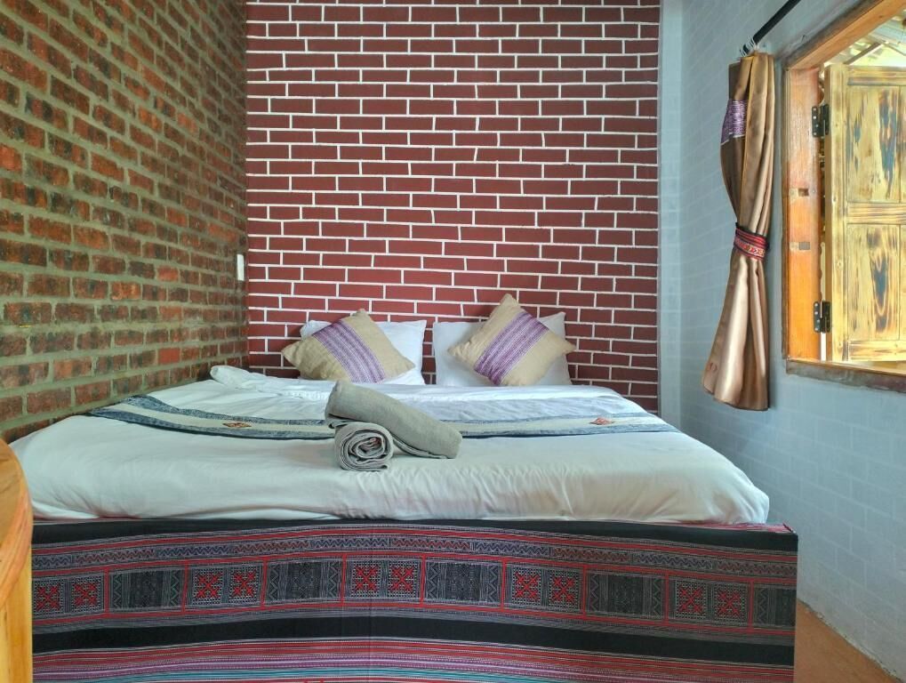 Un lit avec une couvre-lit à motifs, des oreillers et une serviette enroulée.