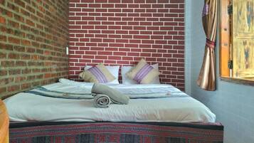 Un lit avec une couvre-lit à motifs, des oreillers et une serviette enroulée.